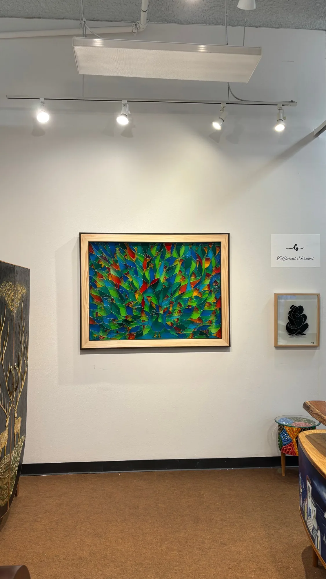 Feathers of Color, a stained glass peacock, on the wall of the Different Strokes booth at High Point Market